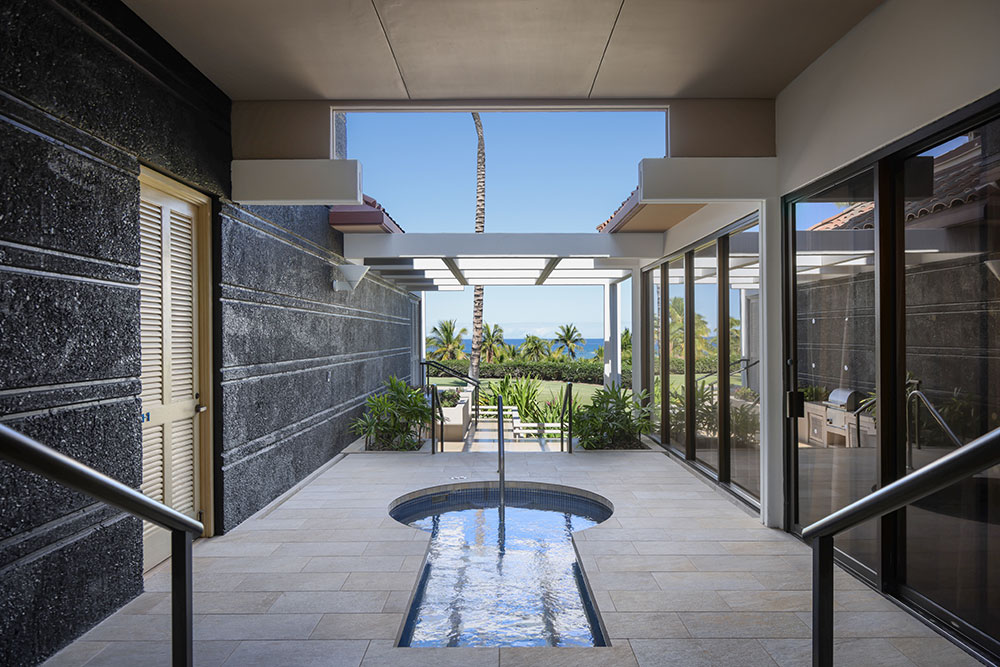 Modern outdoor patio with water feature and ocean view, luxury home construction Hawaii.