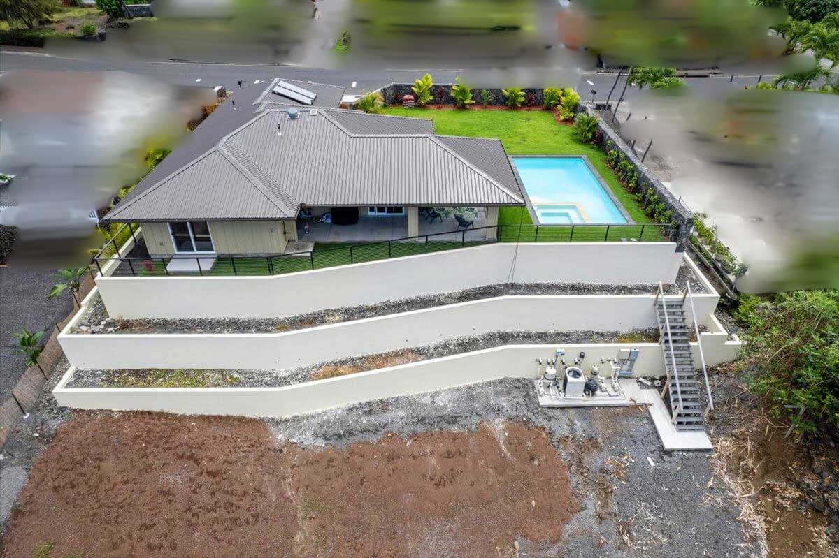 Aerial view of a modern residential home with a backyard pool and landscaped yard in Hawaii.